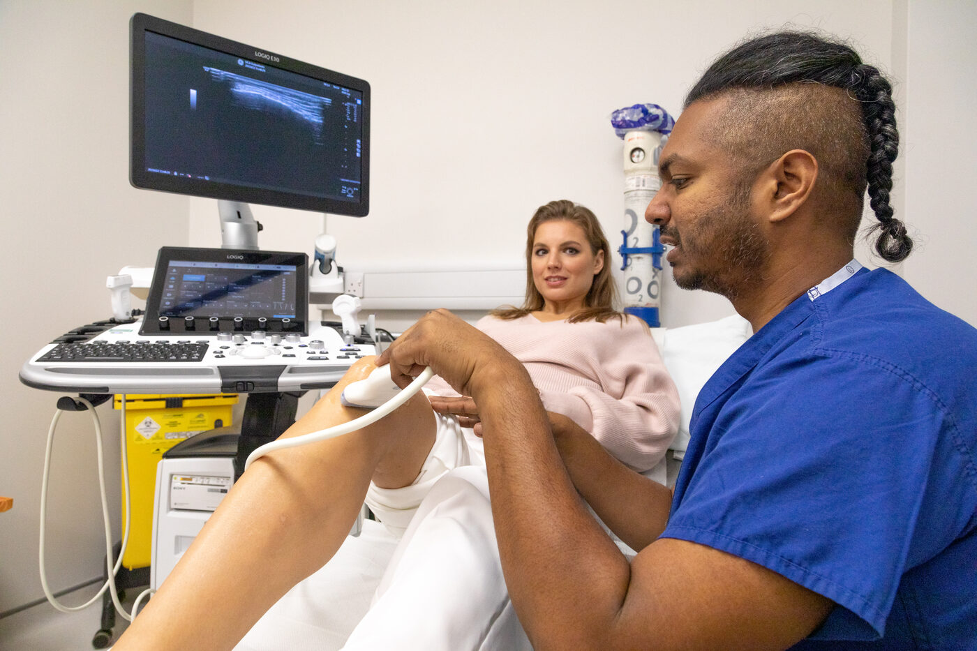 Ultrasound probe on the knee with the scan image on screen, Dr Arj Imbuldeniya knee injection clinic